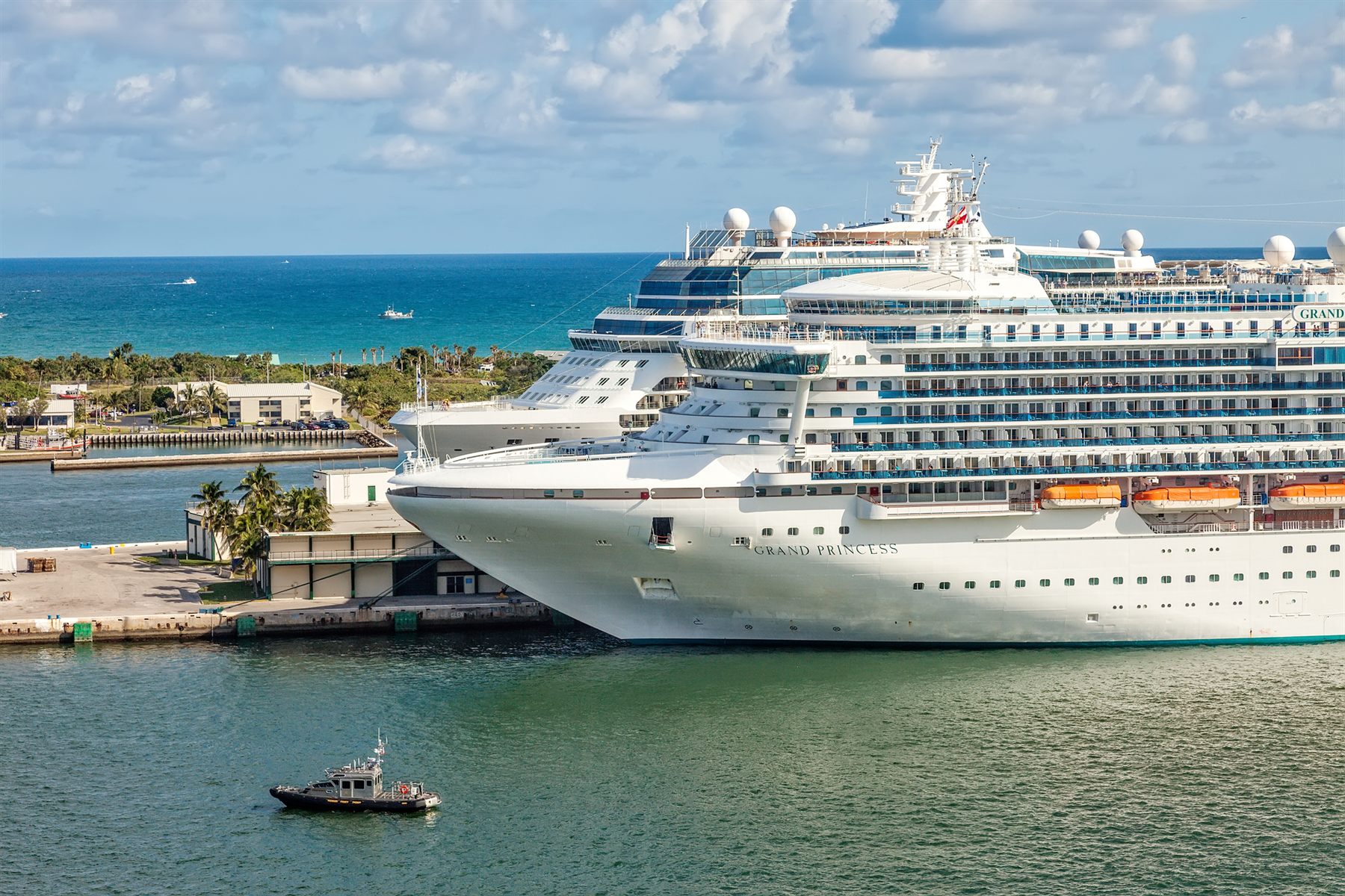 Grand Princess and another cruise ship docked beside a turquoise ocean inlet