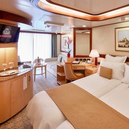 A Cunard Princess Grill suite with a double bed, sofa and balcony doors
